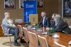 Cztery osoby, dwóch mężczyzn i dwie kobiety siedzą przy stole podczas rozmowy. Uśmiechają się.  W tle baner z napisem Politechnika Rzeszowska.