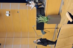 Zdjęcie przedstawia moment dyskusji w nowoczesnej sali audytoryjnej. Po lewej stronie kadru stoi kobieta ubrana na czarno z mikrofonem w dłoni.  Po prawej stronie siedzi prelegentka z mikrofonem, odpowiadając na pytanie.