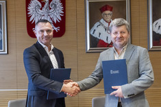 Na zdjęciu dwóch mężczyzn w garniturach podaje sobie dłonie, w ręku trzymają dokumenty w okładkach z napisem Politechnika Rzeszowska.