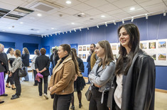 Zdjęcie grupy osób na tle wystawy. Na pierwszym planie trzy młode kobiety, uśmiechają się.