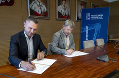 Na zdjęciu dwóch mężczyzn w garniturach podpisuje dokumenty.  W tle na ścianie portrety rektorów i baner z napisem Politechnika Rzeszowska.