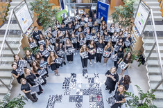 Zdjęcie wykonane z góry. Pośrodku pomiędzy schodami zgromadzonych jest kilkadziesiąt osób, wszyscy ubrani na czarno.