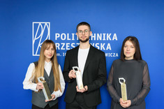 Nagrodzeni w konkursie Paulina Wiecek, Przemysław Dybaś oraz Joanna Krasoń stoją na tle niebieskiej ściany z logo PRz