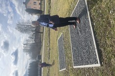 Na zdjęciu widzimy mężczyznę stojącego na ziemiance przykrytej kamieniami i otoczonej krawężnikami. Było to miejsce gdzie przetrzymywano ludzi w czasie trwania obozu. 