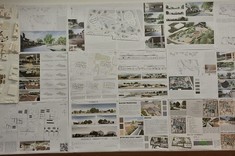 Na ścianie wywieszone plansze na białym tle umieszczone kolorowe grafiki wraz z opisami. Od góry zawieszone cztery makiety w jasnej kolorystyce przedstawiające projekt targowiska wraz z najbliższym otoczeniem.
