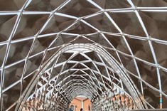 Przejście wykończone pełną drewnianą podłogą i balustradą w jasnoszarym kolorze. Nad przejściem zadaszenie w formie łuku. Zadaszenie zbudowane z metalowych kwadratów rozpiętych w równych odstępach. Odstępy miedzy kwadratami delikatnie doświetlają przejście.