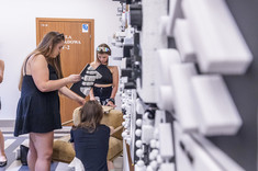 Dwie kobiety przypinają do tablicy biało-czarne makiety.